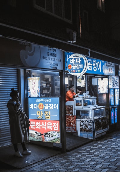 白天站在商店门前的穿黑夹克的男人